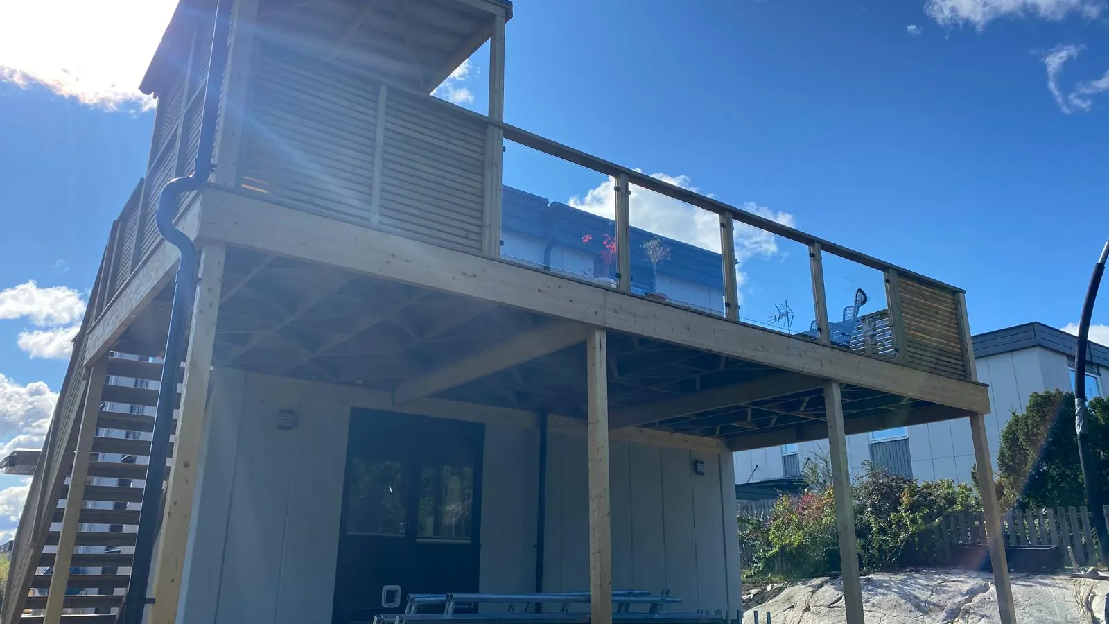 Høy terrasse i tre med trapp og levegg, bygget av Moisés.