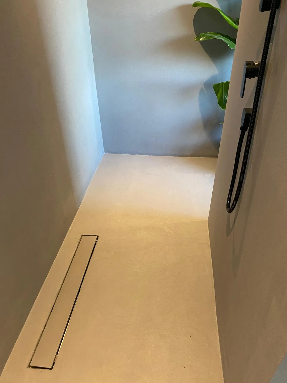 Dusjen med renne i gulvet og svart dusj på veggen.