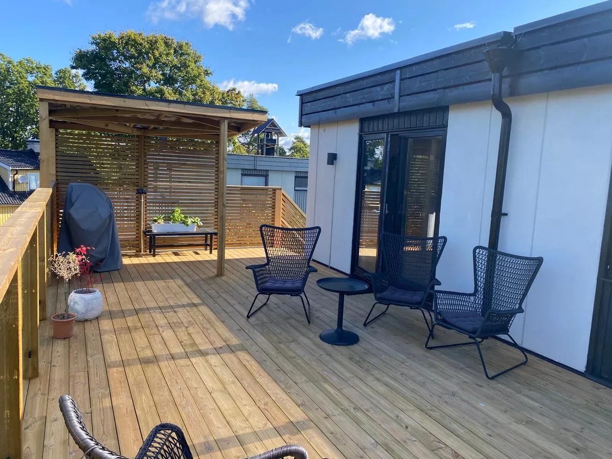 Terrasse i tre med levegg og tak over sittegruppen.