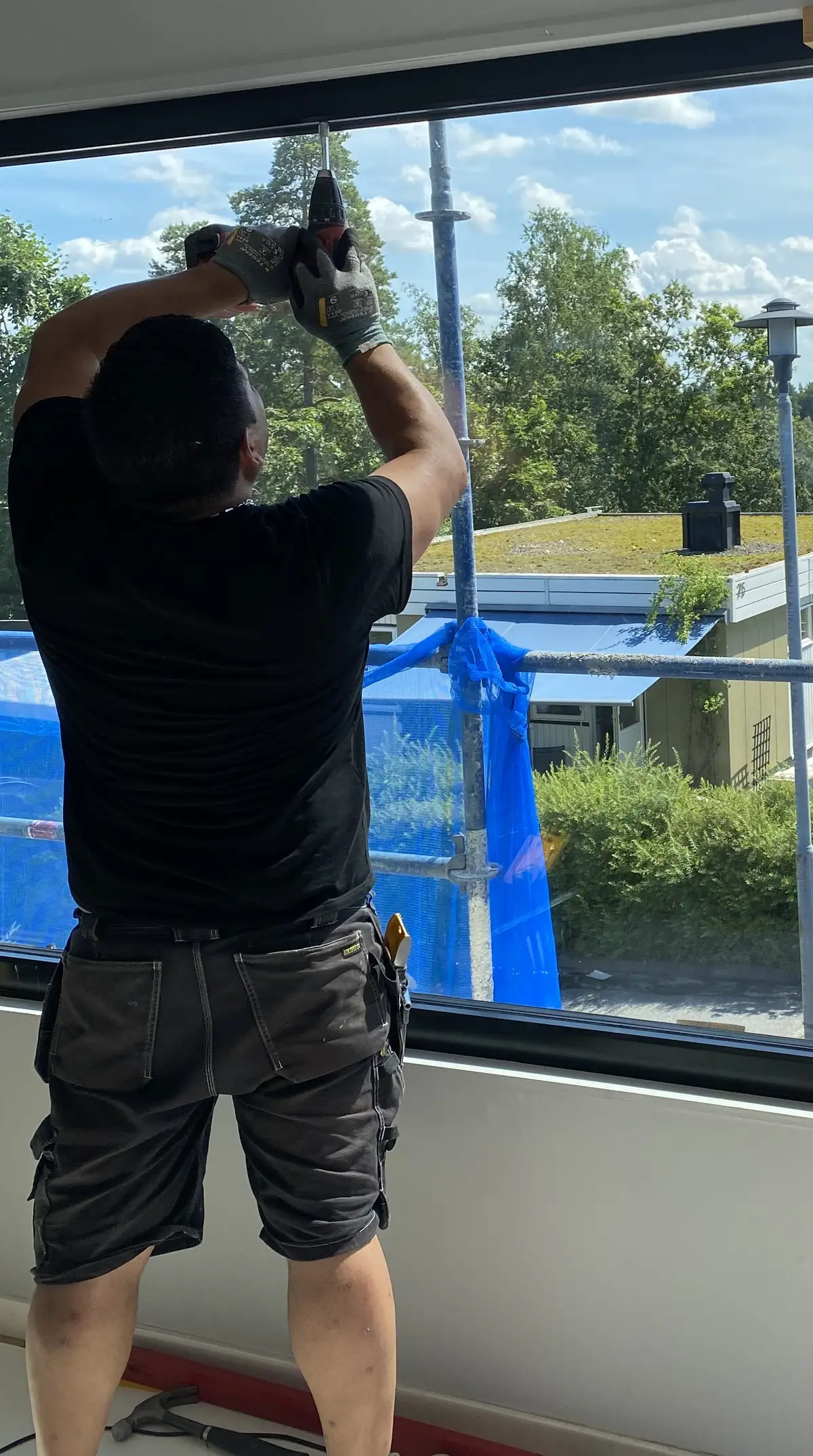 Moisés setter inn et stort vindu innenfra, med stillaset utenfor.